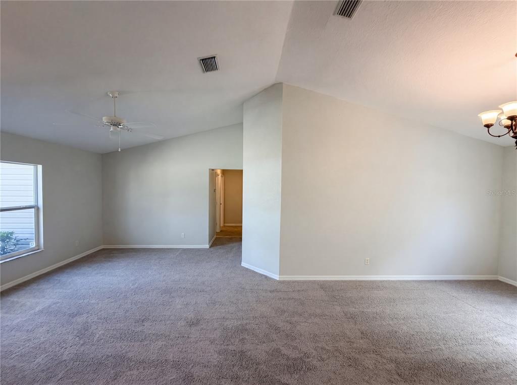 An empty room with gray carpet, light-colored walls, a ceiling fan, and a vaulted ceiling — 517 BAHIA CIRCLE RUN, OCALA, FL