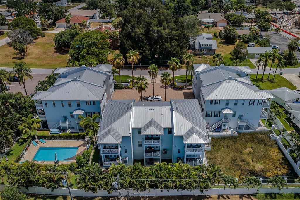 An aerial view of a multi-story blue apartment complex with a swimming pool and palm trees — 7010 GREVILLA AVENUE S, SOUTH PASADENA, FL