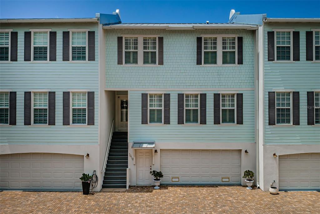 A three-story townhouse with light blue siding, a two-car garage, and a front staircase — 7010 GREVILLA AVENUE S, SOUTH PASADENA, FL