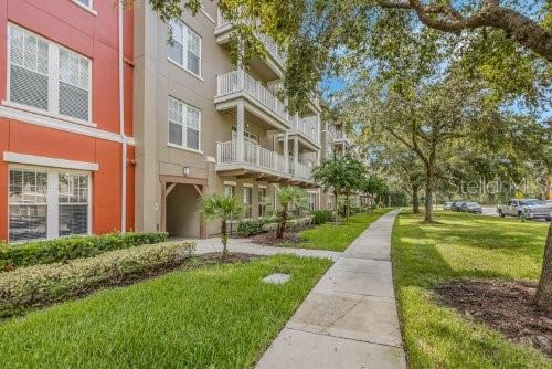 A multi-story apartment building with balconies stands next to a sidewalk and green lawn — 1410 CELEBRATION AVENUE UNIT 407, CELEBRATION, FL