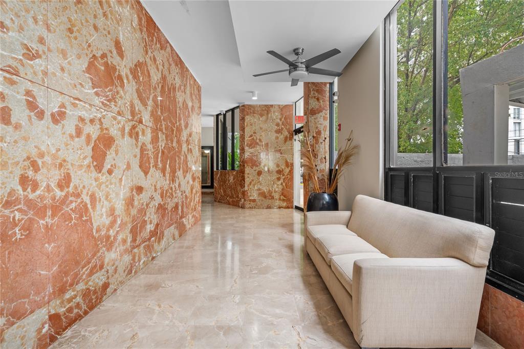 A lobby area features orange marble walls, a beige sofa, and a ceiling fan — 1223 LUCHETTI STREET UNIT 7S, SAN JUAN, PR