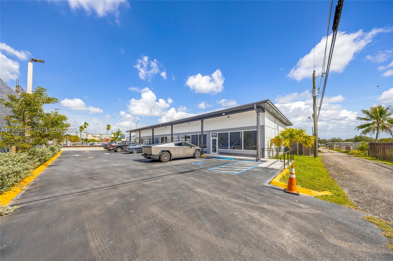 A single-story commercial building with a parking lot and a parked Tesla Cybertruck — 4030 Pembroke Rd, Hollywood FL 33021, HOLLYWOOD, FL