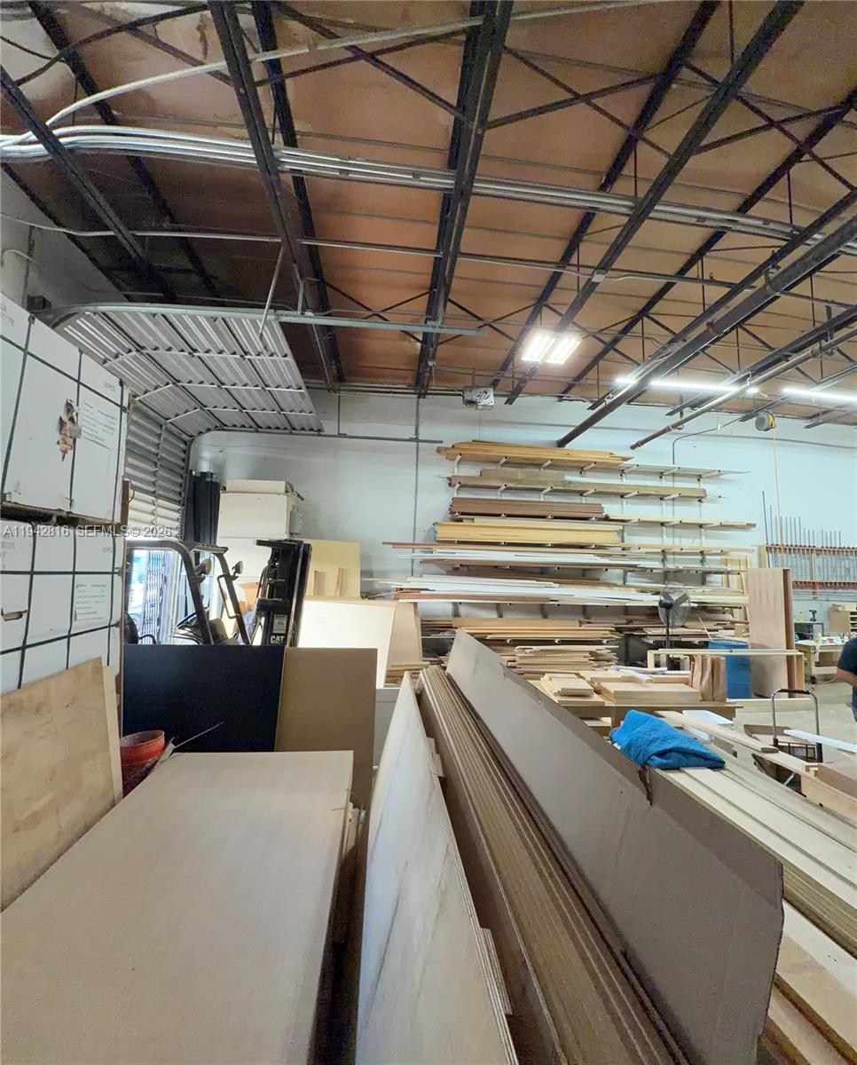 A warehouse interior features stacked lumber, a forklift, and exposed metal ceiling trusses — 733 W 26th St # 733, Hialeah FL 33010, HIALEAH, FL