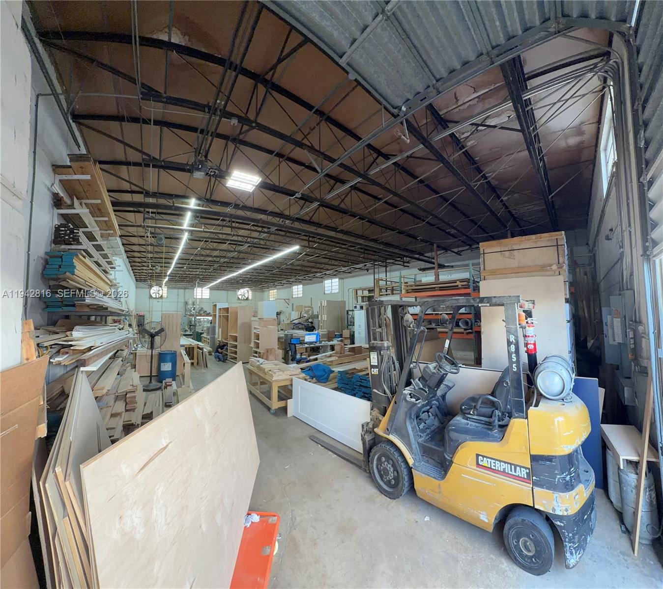 A large industrial workshop features a yellow Caterpillar forklift, wooden shelving, and exposed ceiling beams — 733 W 26th St # 733, Hialeah FL 33010, HIALEAH, FL