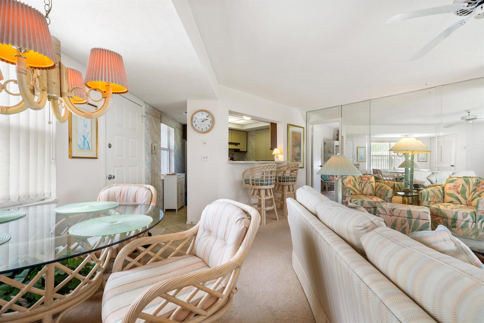 A dining area and living room feature rattan furniture, a glass table, and mirrored walls — 3236 SE Aster Lane # M226, Stuart FL 34994, STUART, FL