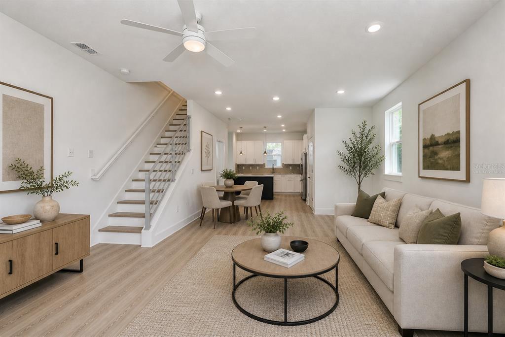 This open-concept living and dining area features light wood flooring, a staircase, and modern finishes — 4171 56TH AVENUE N, ST PETERSBURG, FL