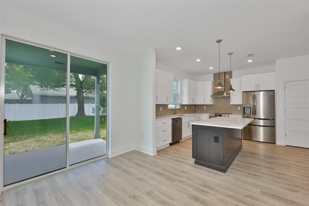 A kitchen with white cabinets, a dark island, stainless steel appliances, and a sliding glass door — 4171 56TH AVENUE N, ST PETERSBURG, FL