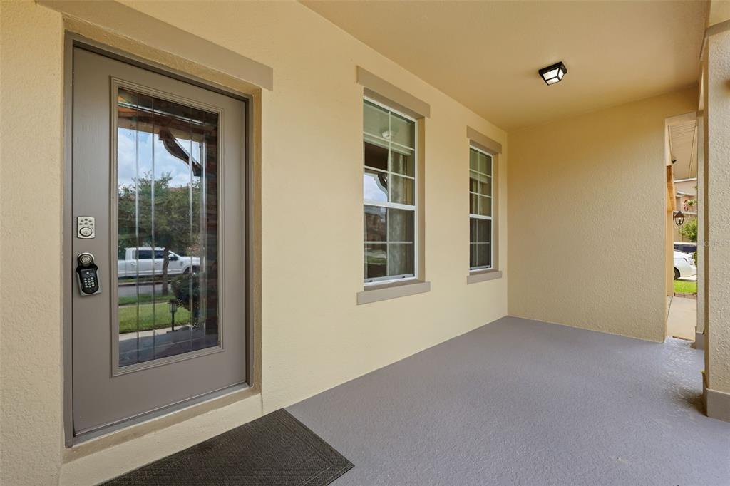 A covered front porch features a gray door with a glass insert and two windows — 3018 BOATING BOULEVARD, KISSIMMEE, FL