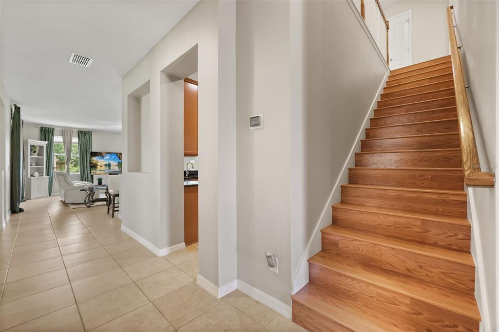 A tiled entryway features a wooden staircase on the right and an open living area — 3018 BOATING BOULEVARD, KISSIMMEE, FL