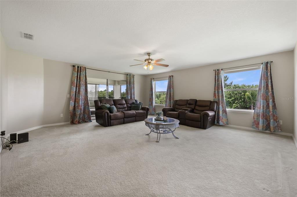 A living room features beige carpet, two brown leather sofas, a coffee table, and curtains — 3018 BOATING BOULEVARD, KISSIMMEE, FL