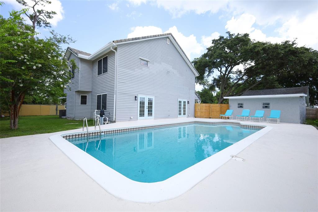 A two-story house with light gray siding features a backyard swimming pool and patio — 1636 TUSCALOOSA AVENUE, HOLLY HILL, FL