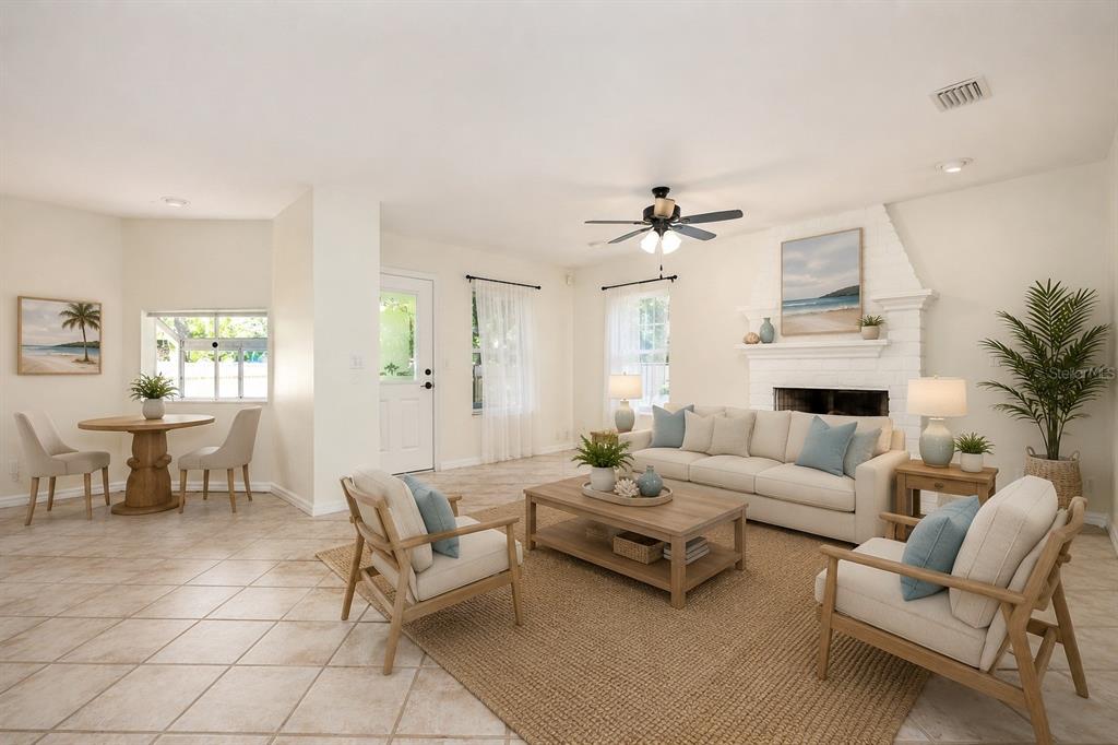 A bright living room features a white brick fireplace, tile flooring, and a dining area — 1636 TUSCALOOSA AVENUE, HOLLY HILL, FL
