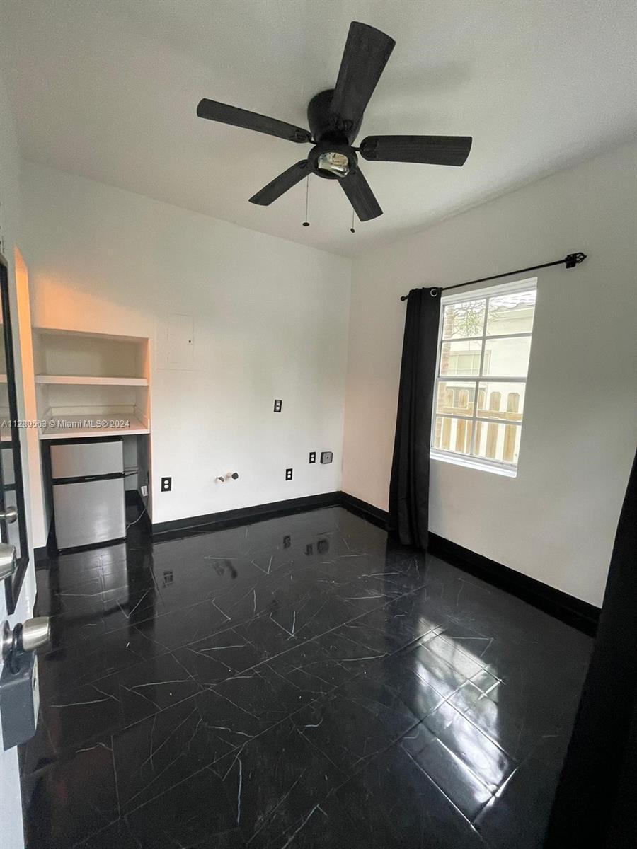 A small room features black marble-patterned tile flooring, a ceiling fan, and a built-in shelf — 1455 Michigan Ave # 7, Miami Beach FL 33139, MIAMI BEACH, FL