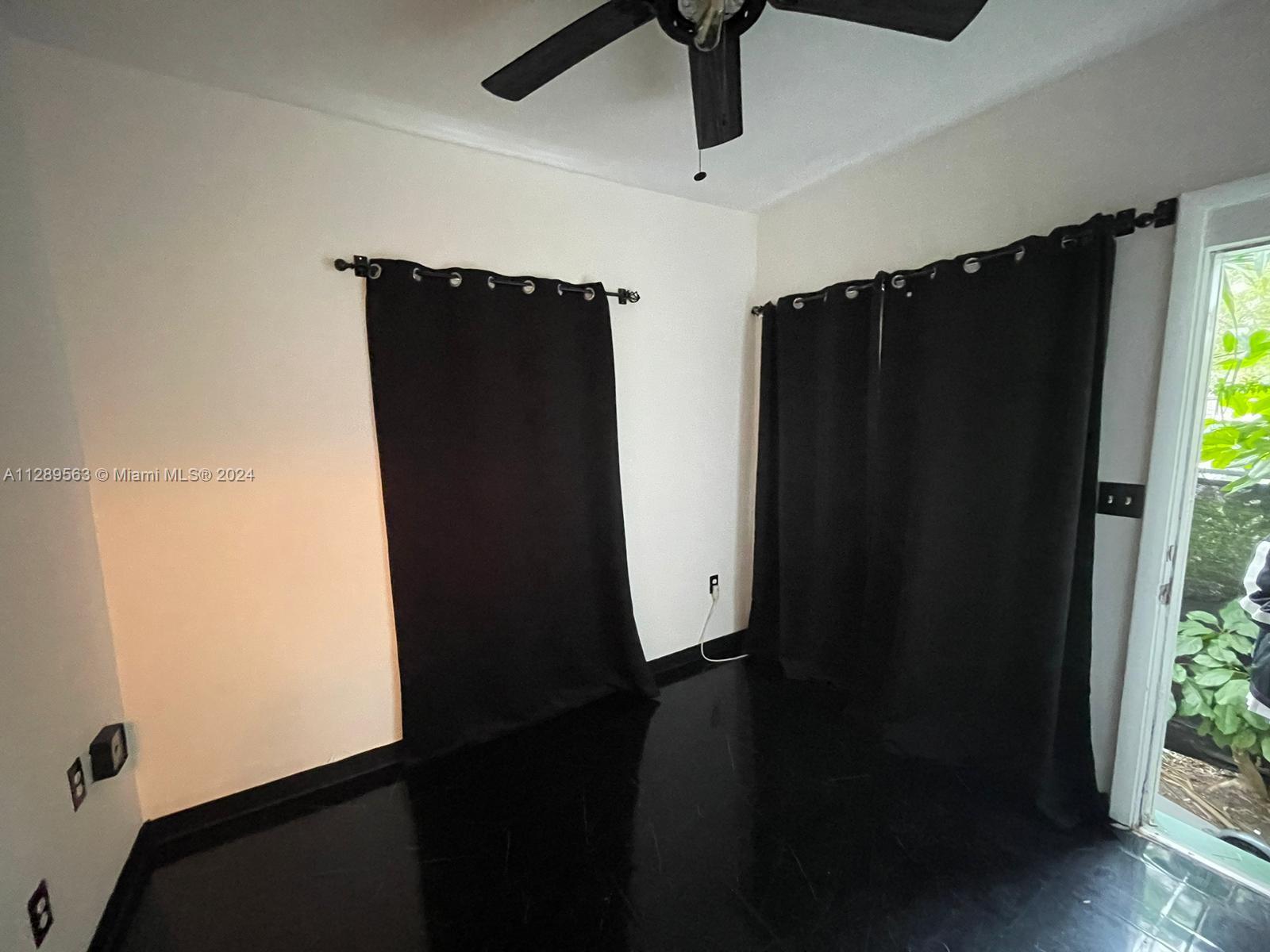 A room with black floors, black curtains, and a ceiling fan — 1455 Michigan Ave # 7, Miami Beach FL 33139, MIAMI BEACH, FL