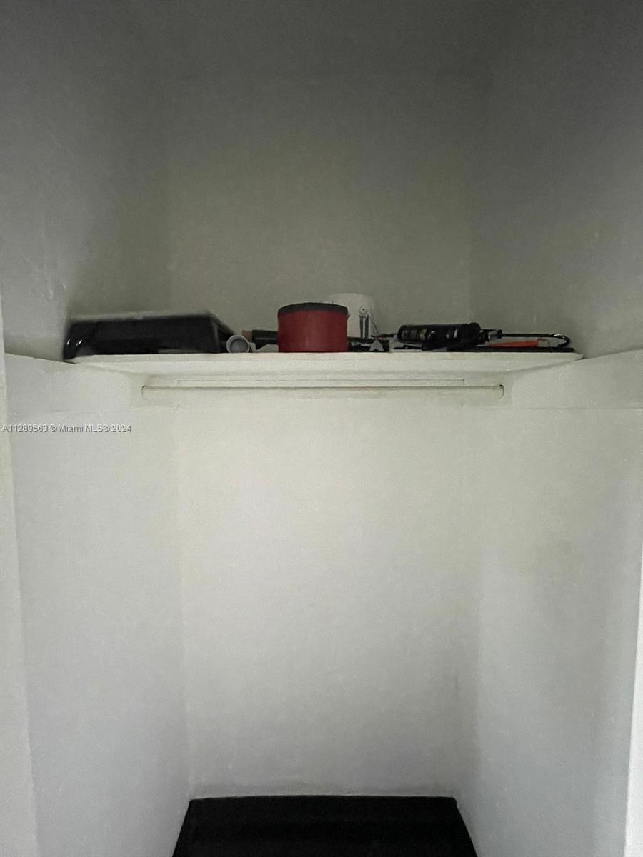 A small, white closet features a single shelf holding various household items — 1455 Michigan Ave # 7, Miami Beach FL 33139, MIAMI BEACH, FL
