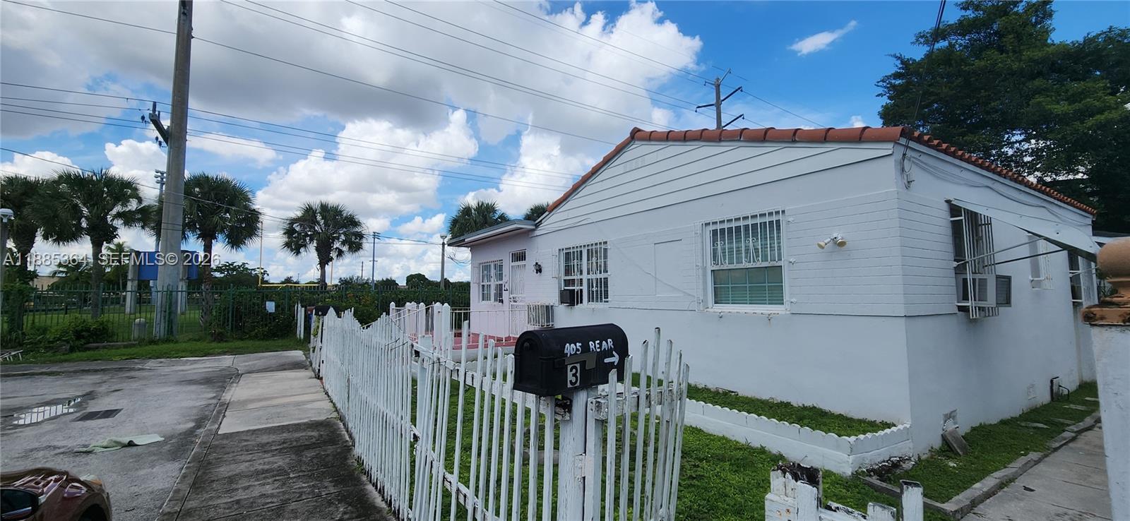 A white single-story house with a fenced yard and a mailbox labeled 405 Rear — 405 NW 64th St, Miami FL 33150, MIAMI, FL