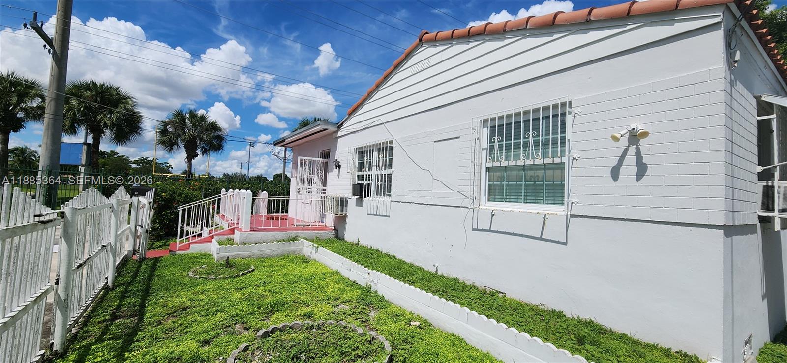A white, single-story house with a tiled roof, security bars on windows, and a lawn — 405 NW 64th St, Miami FL 33150, MIAMI, FL