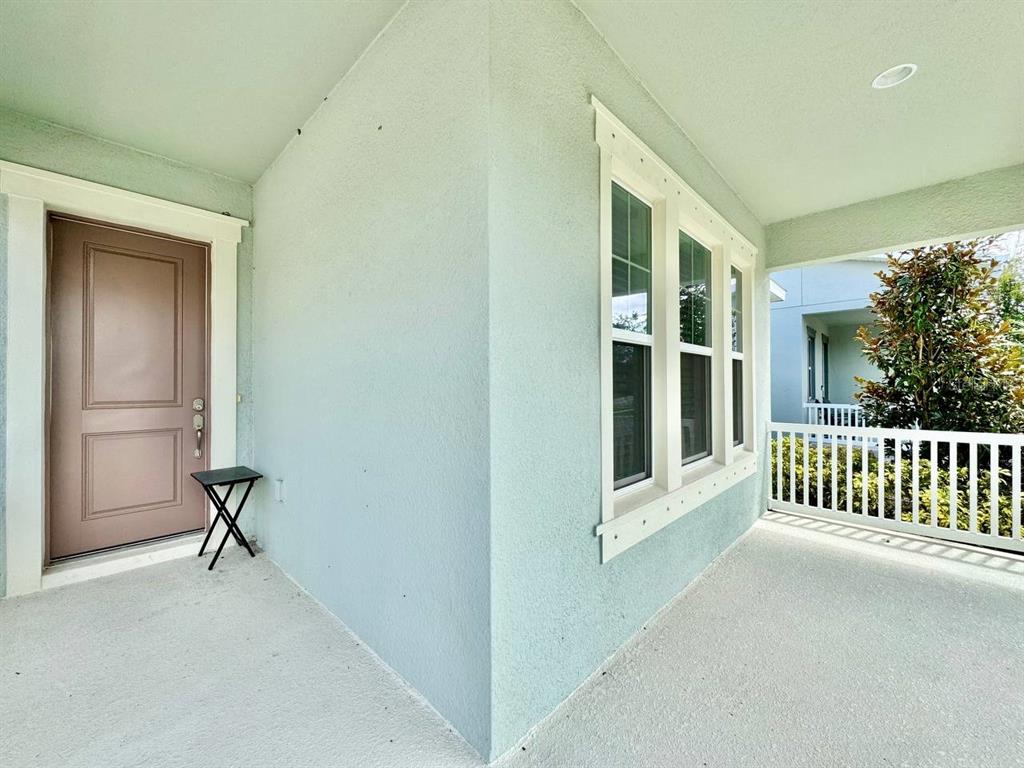A covered front porch features light blue stucco walls, a brown door, and white railings — 827 WINTERSIDE DRIVE, APOLLO BEACH, FL