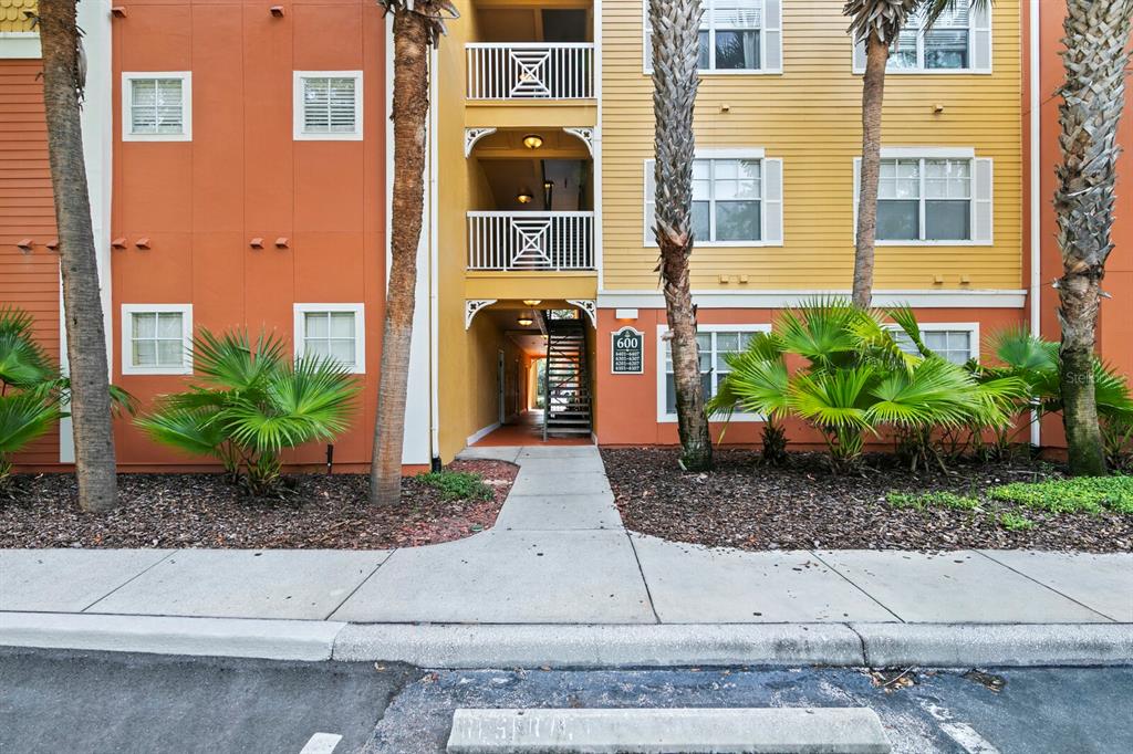 Exterior view of a multi-story apartment building with orange and yellow siding and palm trees — 4207 S DALE MABRY HIGHWAY UNIT 6107, TAMPA, FL