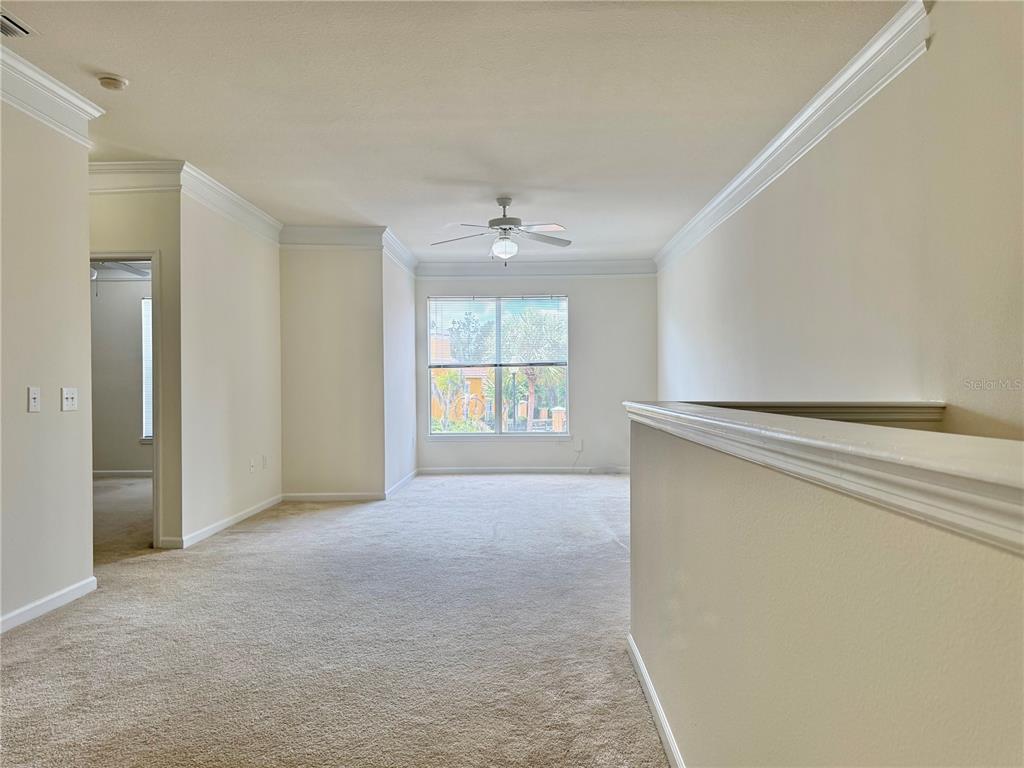 A carpeted room with a ceiling fan, crown molding, and a window overlooking trees — 8801 VILLA VIEW CIRCLE UNIT 202, ORLANDO, FL