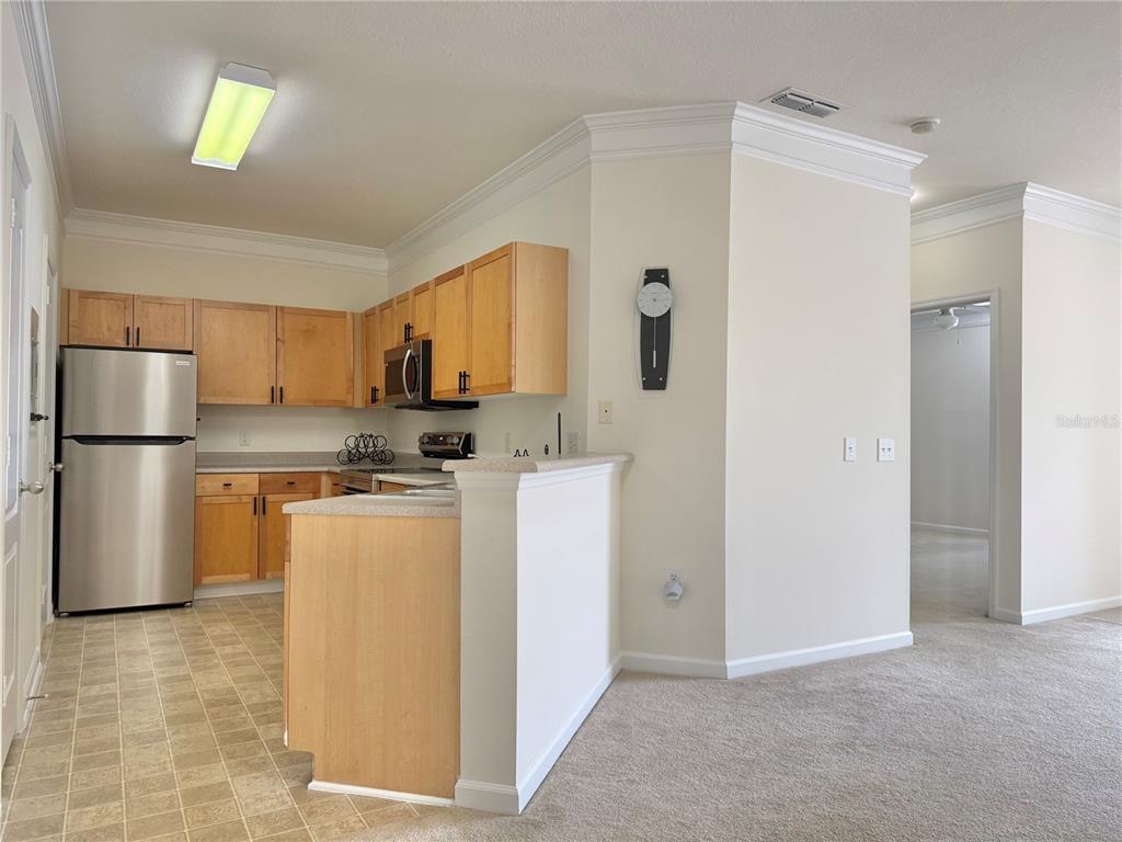 A kitchen with light wood cabinets, stainless steel appliances, and a breakfast bar — 8801 VILLA VIEW CIRCLE UNIT 202, ORLANDO, FL