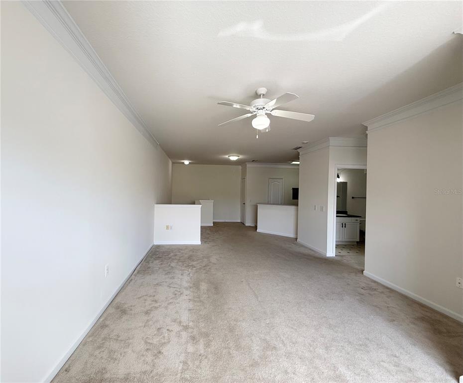 An empty carpeted room features a ceiling fan, crown molding, and an adjacent bathroom — 8801 VILLA VIEW CIRCLE UNIT 202, ORLANDO, FL