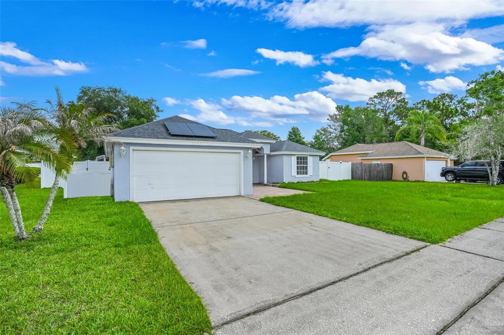 A single-story house with a white garage door, solar panels, and a concrete driveway — 20123 MAXIM PARKWAY, ORLANDO, FL