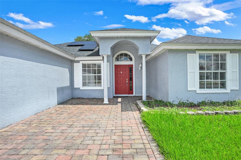 A light blue house exterior features a red front door, white shutters, and paver driveway — 20123 MAXIM PARKWAY, ORLANDO, FL