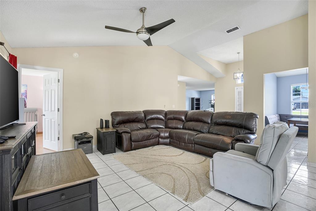 A living room features a large brown sectional, a grey recliner, and white tile flooring — 20123 MAXIM PARKWAY, ORLANDO, FL