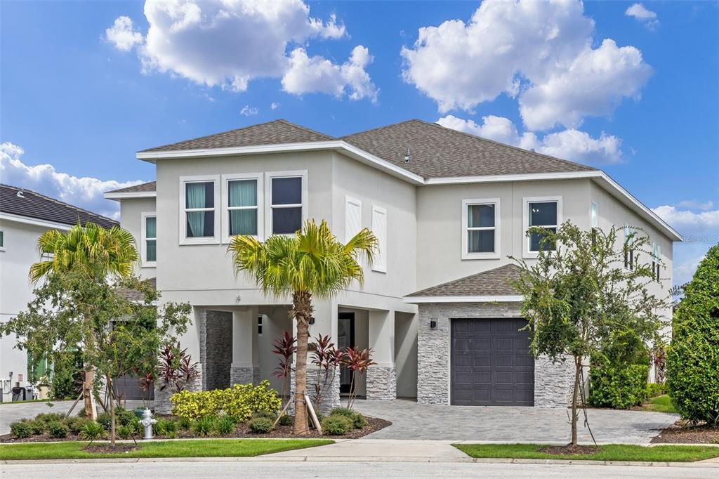 A two-story house with a light-colored stucco exterior, stone accents, and a paved driveway — 977 DESERT MOUNTAIN COURT, REUNION, FL