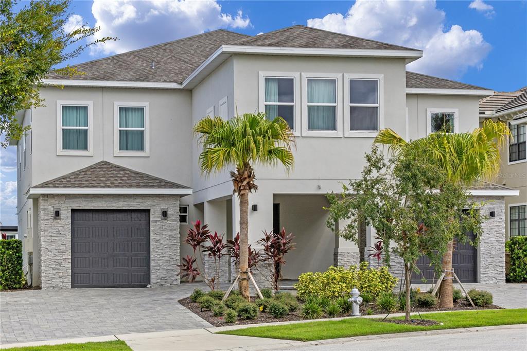 A two-story house with a stone-accented facade, two garage doors, and palm trees in front — 977 DESERT MOUNTAIN COURT, REUNION, FL
