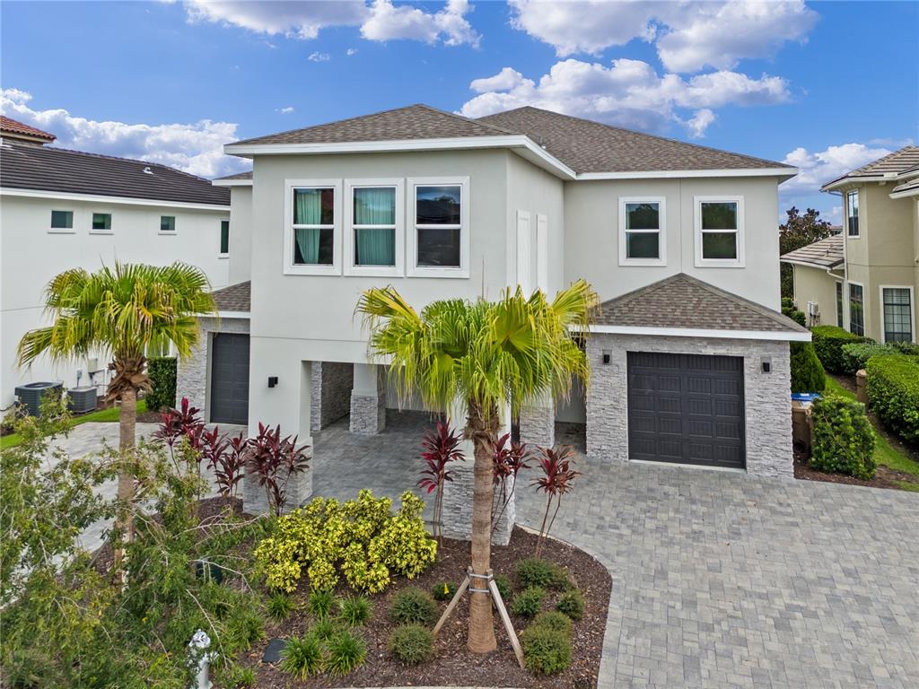 A two-story house with a paved driveway, stone accents, and two garage doors — 977 DESERT MOUNTAIN COURT, REUNION, FL