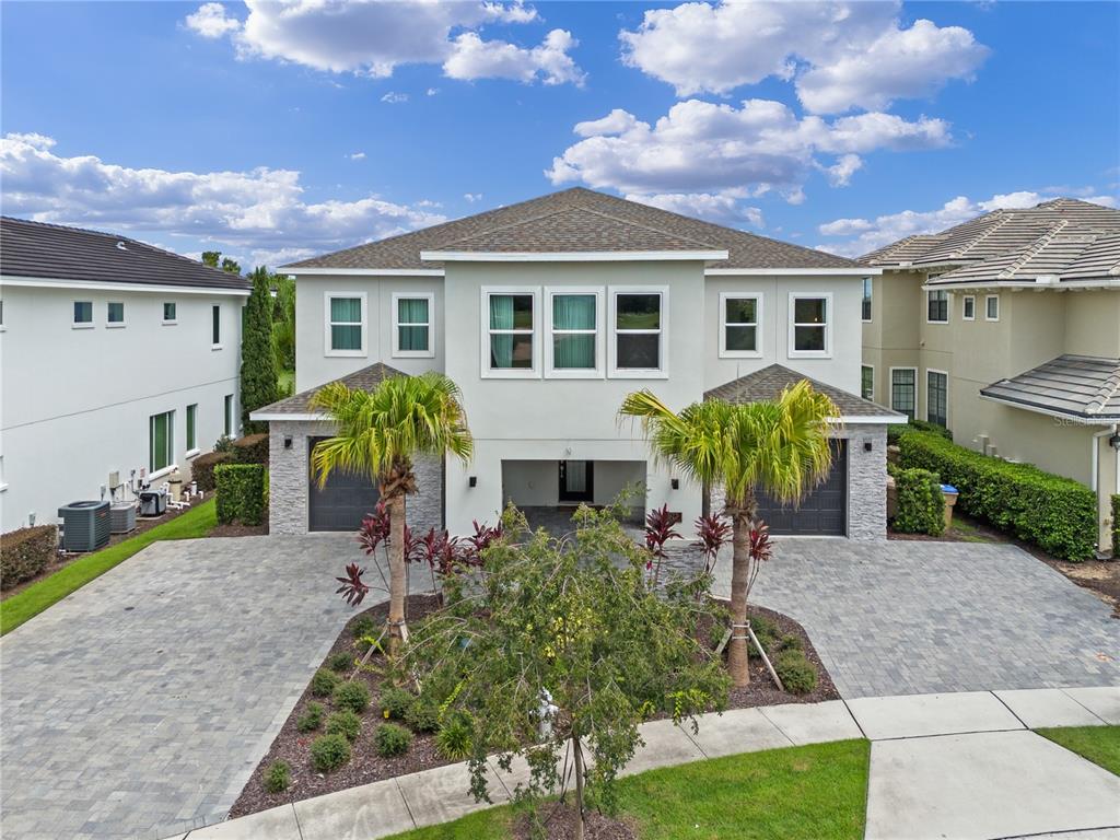 A two-story house features a paved driveway, two garages, and a central covered entryway — 977 DESERT MOUNTAIN COURT, REUNION, FL