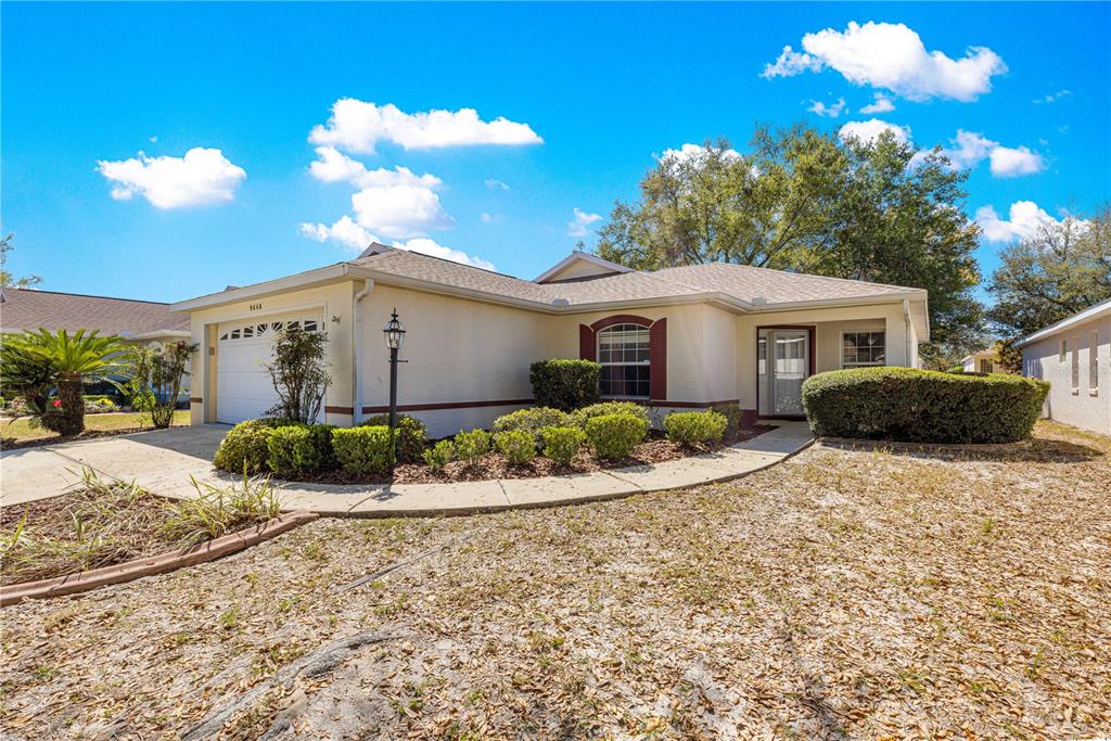 A single-story house with a beige stucco exterior, a garage, and a curved walkway — 9646 SW 92ND PLACE ROAD, OCALA, FL