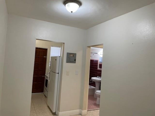 A view of a hallway leading to a kitchen with a refrigerator and a bathroom — MIAMI BEACH, FL
