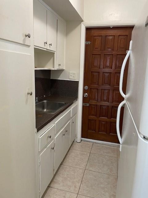 A small kitchen features white cabinets, a stainless steel sink, and a wooden door — MIAMI BEACH, FL