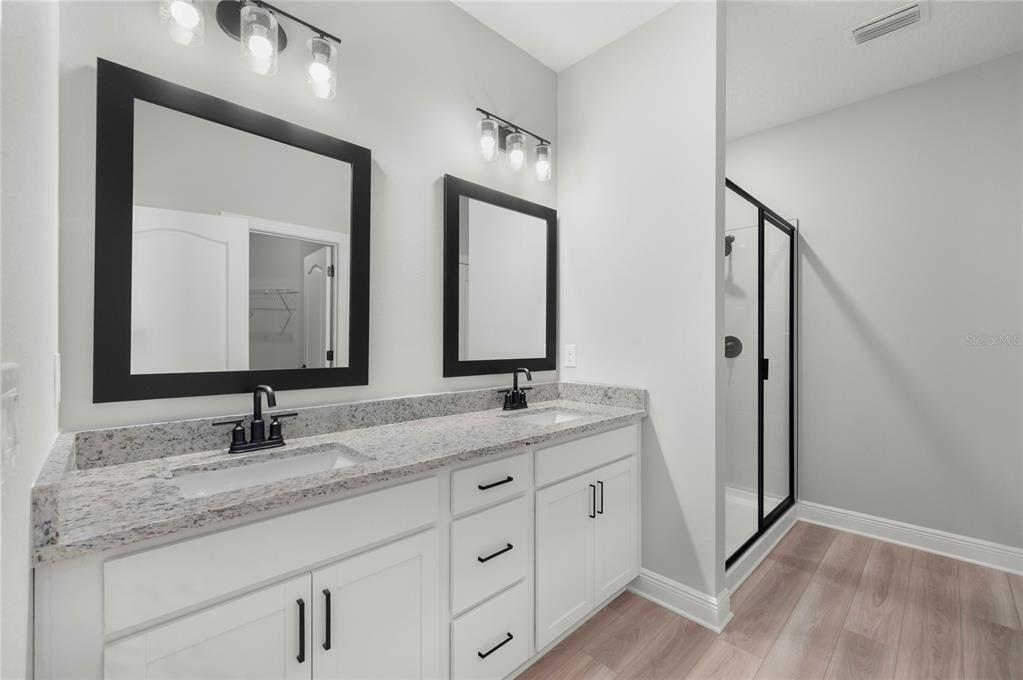 A bathroom features a double vanity with white cabinets, granite countertops, and black fixtures — 7813 MARLOW PLACE, KISSIMMEE, FL
