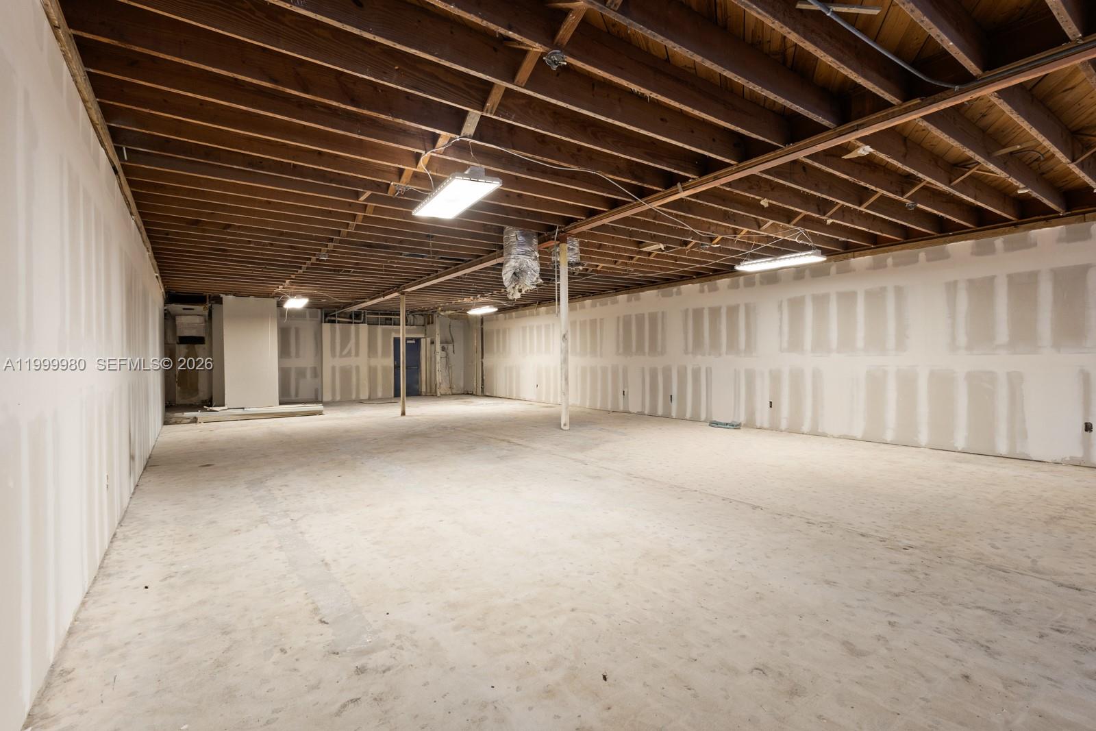 An unfinished commercial space features exposed wood ceiling joists, drywall-covered walls, and concrete flooring — 620 Crandon Blvd # 7, Key Biscayne FL 33149, KEY BISCAYNE, FL