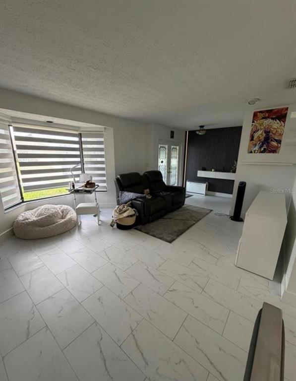 A living room features white marble-look tile flooring, a black loveseat, and a bay window — 209 SW 42ND STREET, CAPE CORAL, FL