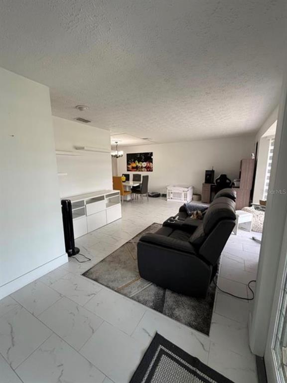 A living room with white tile floors, a black recliner, and a dining area beyond — 209 SW 42ND STREET, CAPE CORAL, FL