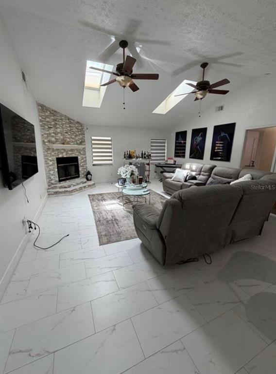 A living room features a stone fireplace, two ceiling fans, skylights, and white tile flooring — 209 SW 42ND STREET, CAPE CORAL, FL