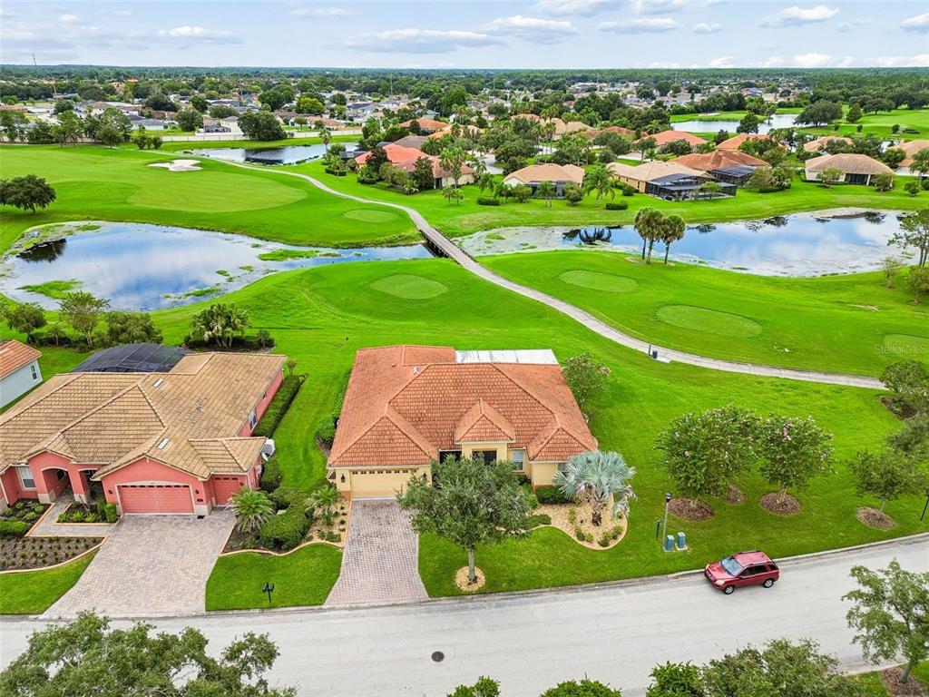 An aerial view shows a single-story house with a tile roof beside a golf course — 600 VOLTERRA BOULEVARD, POINCIANA, FL