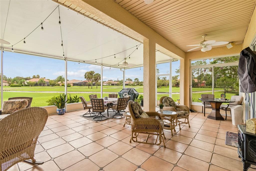 A covered patio with tiled flooring, wicker furniture, and a view of a grassy golf course — 600 VOLTERRA BOULEVARD, POINCIANA, FL