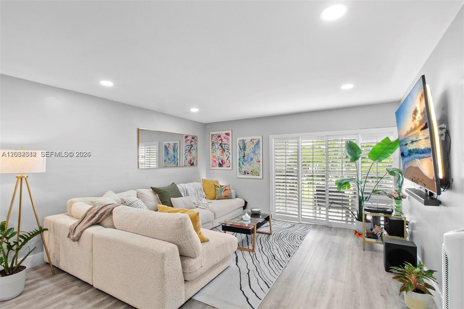 A living room features a cream sectional sofa, patterned rug, and a wall-mounted television — 7725 SW 86th St # 420, Miami FL 33143, MIAMI, FL