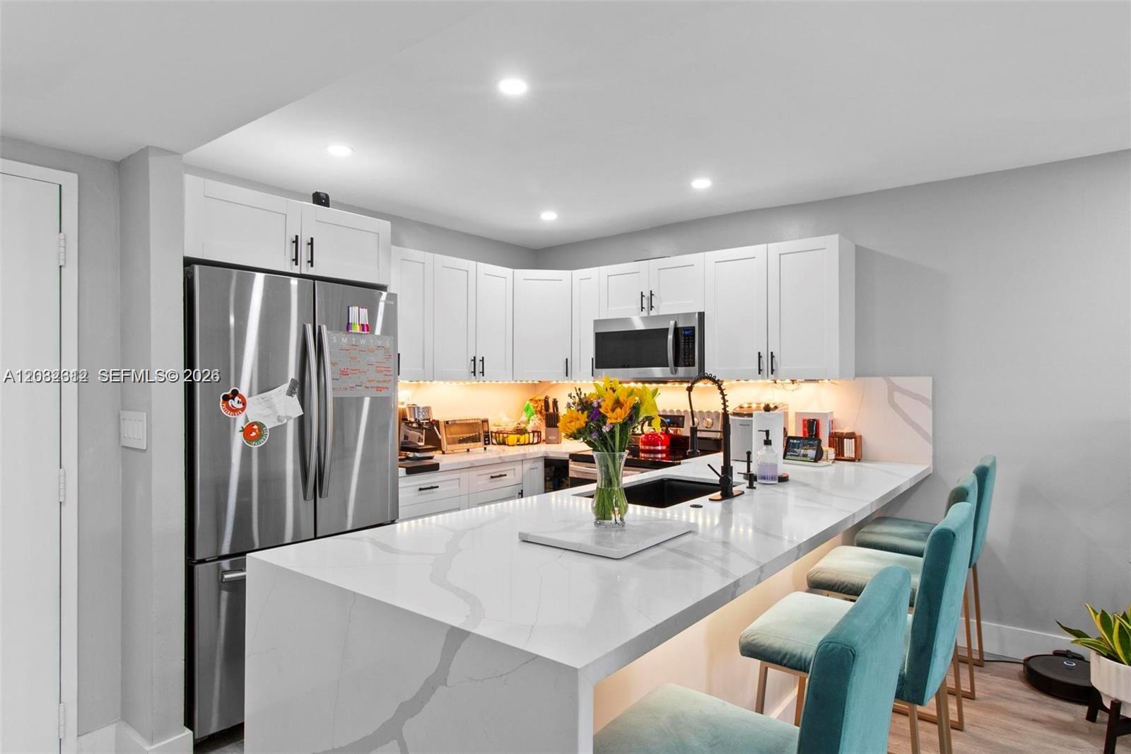 A kitchen features white cabinets, a stainless steel refrigerator, and a marble-topped island with stools — 7725 SW 86th St # 420, Miami FL 33143, MIAMI, FL