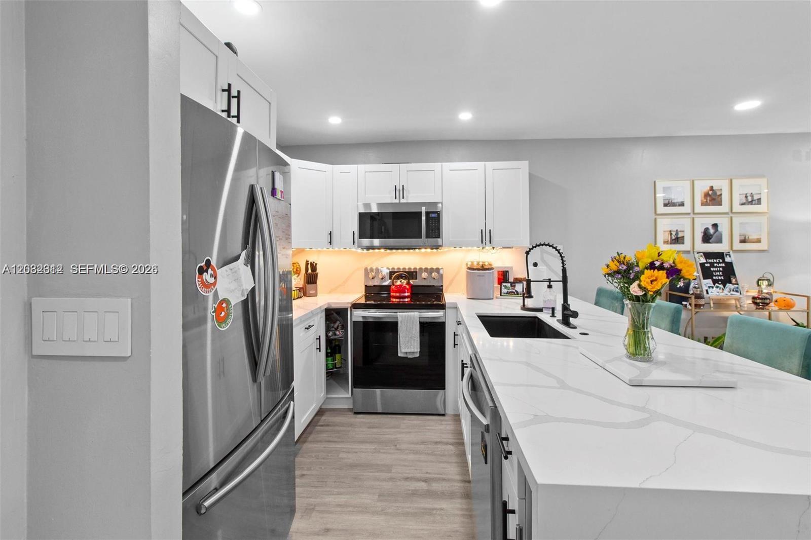 A modern kitchen features white cabinetry, stainless steel appliances, and a large quartz-topped island — 7725 SW 86th St # 420, Miami FL 33143, MIAMI, FL