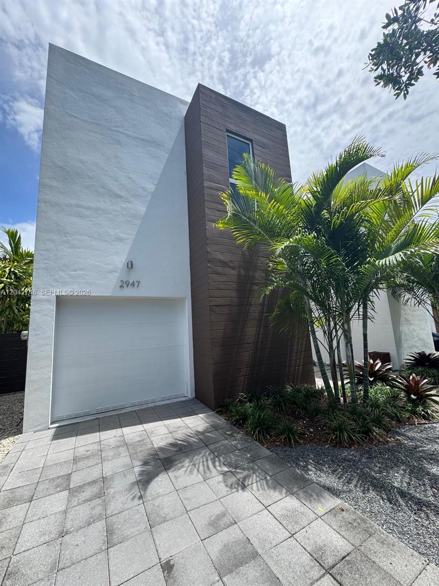 A modern two-story house features a white stucco facade, a brown wood-paneled section, and a garage — 2947 SW 27th Ter # 0, Miami FL 33133, MIAMI, FL
