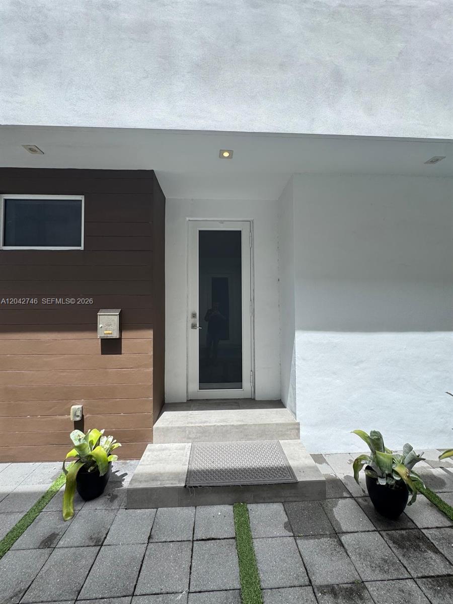 The exterior entrance features a glass door, brown wood-look siding, and two potted plants — 2947 SW 27th Ter # 0, Miami FL 33133, MIAMI, FL