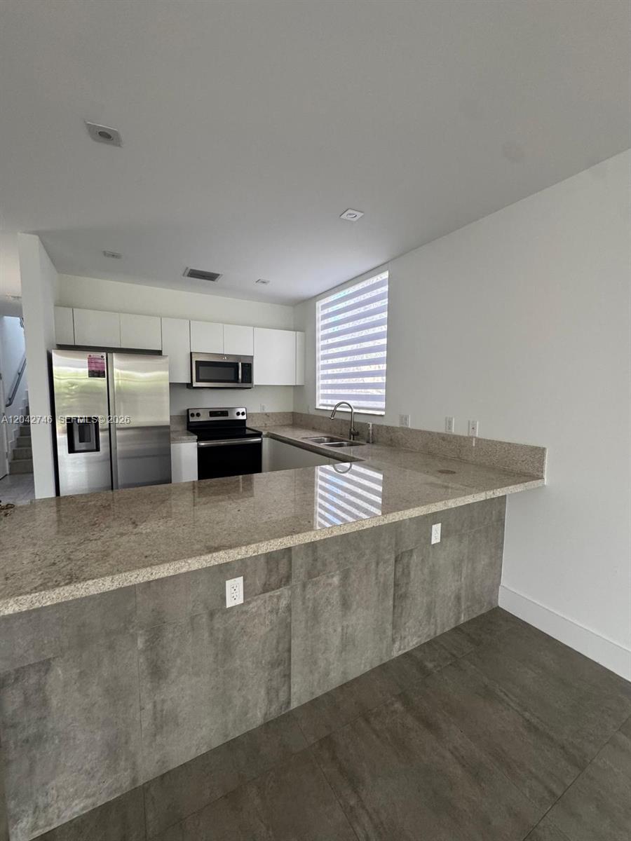 A kitchen features a granite breakfast bar, stainless steel appliances, and white upper cabinets — 2947 SW 27th Ter # 0, Miami FL 33133, MIAMI, FL