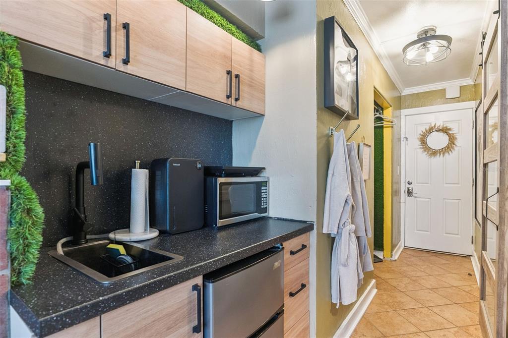 A kitchenette features wood-look cabinets, a black countertop, a small sink, and a microwave — 1233 S ATLANTIC AVENUE UNIT 3140, DAYTONA BEACH, FL